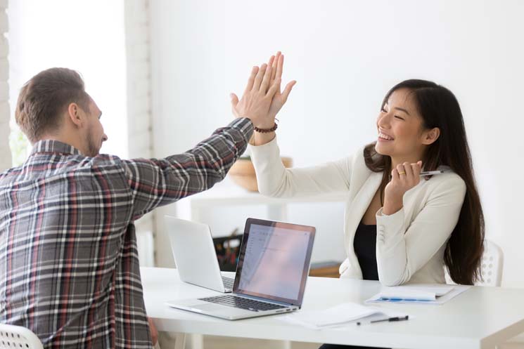 Male and female coworker giving a high five after collaborating accessibly